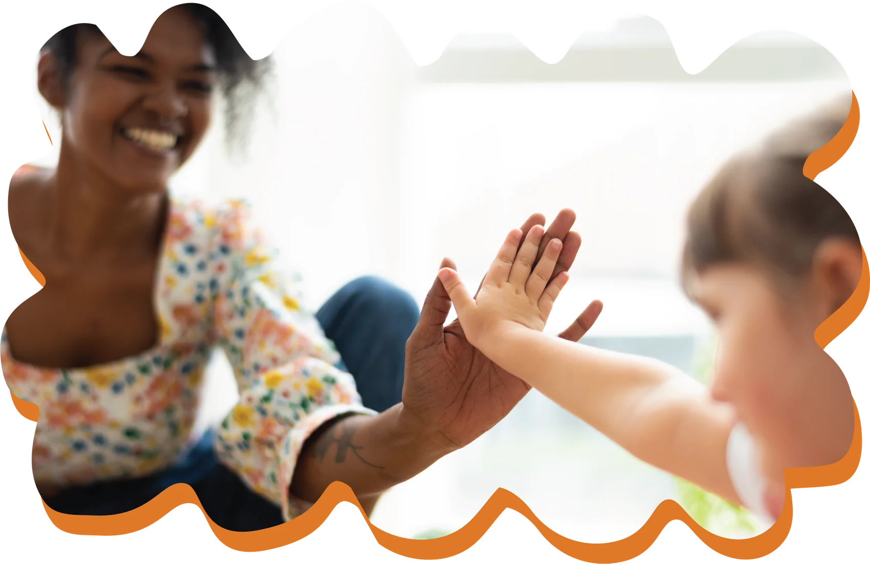 A smiling woman giving a young child a high five