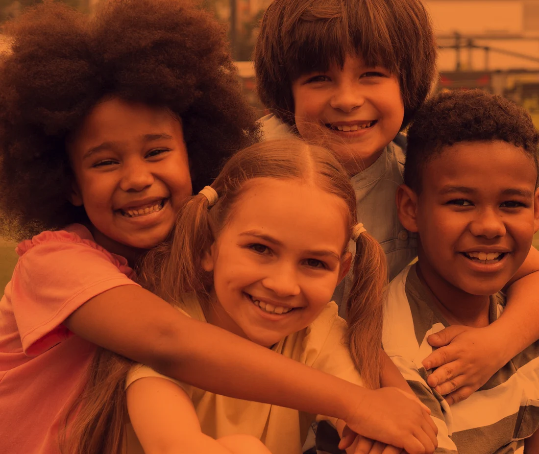 Four children hugging and smiling to camera