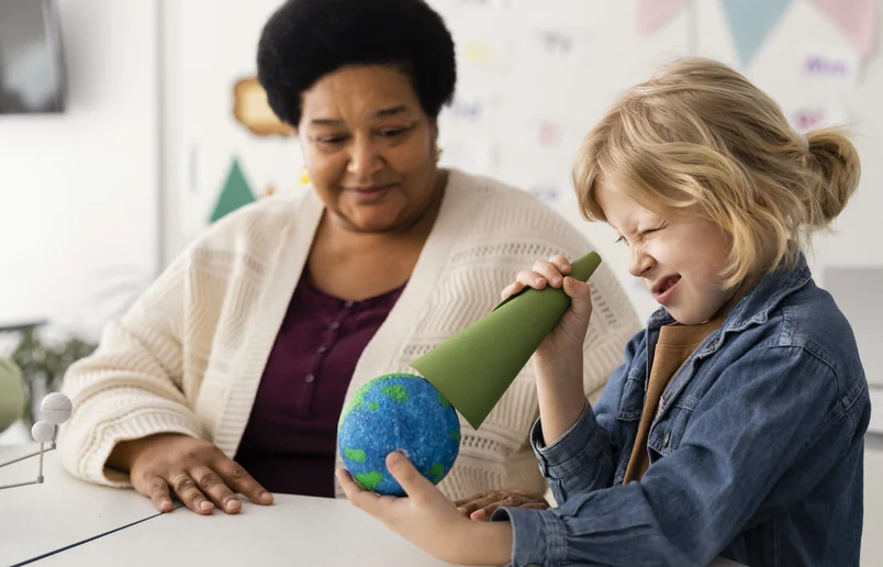 A teacher and a child looking at a globe together