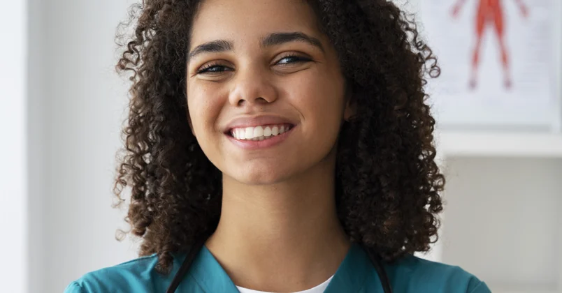 A nurse in scrubs smiling to camera